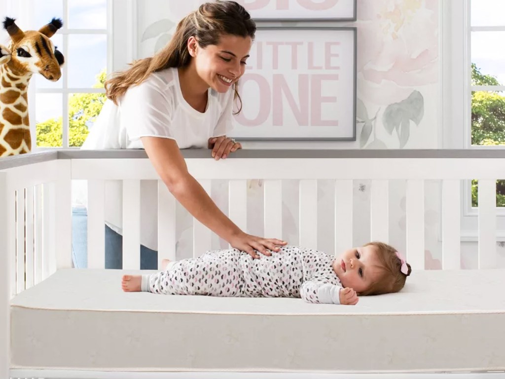 mother touching baby laying down in crib