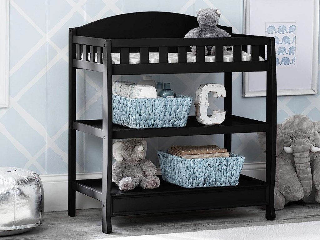 black changing table with decor and blue storage bins on lower shelves