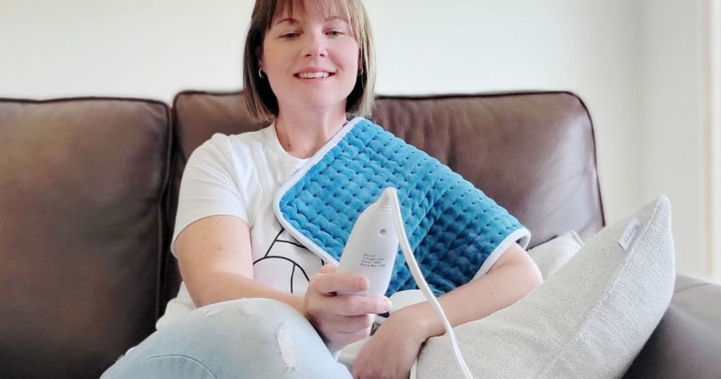 Woman holding the remote for the heating pad on her shoulder