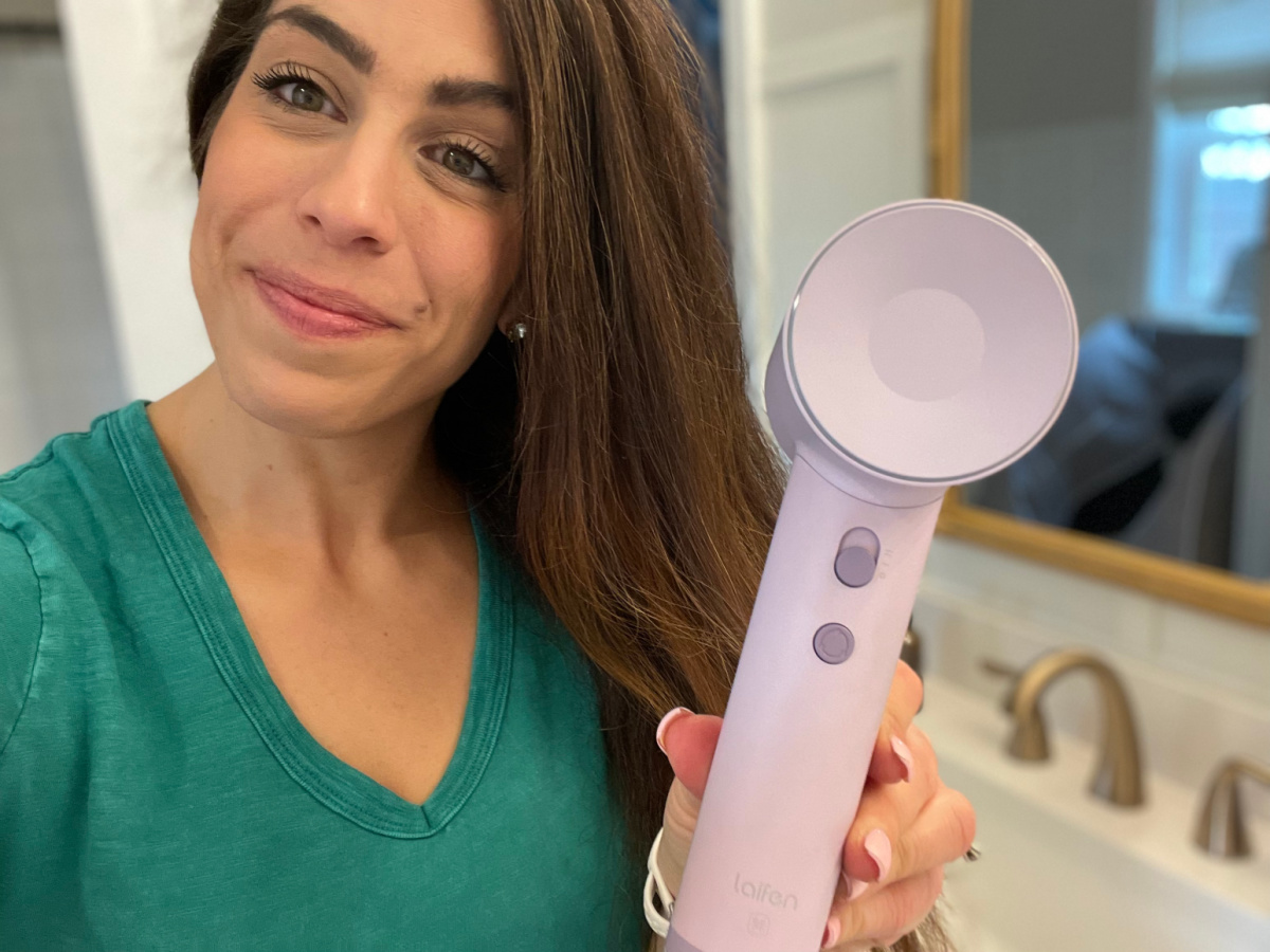 woman with dry shiny hair smiling and holding purple hair dryer