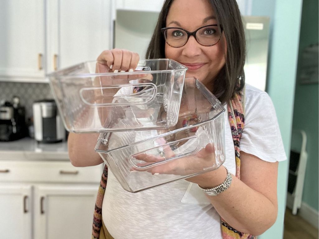 woman holding two clear organizer bins