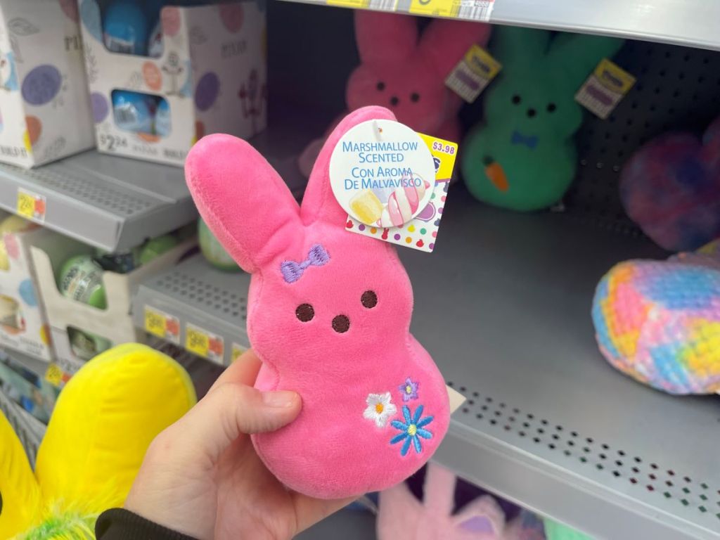 Hand holding a Pink Peeps plush that has flowers on it at a store