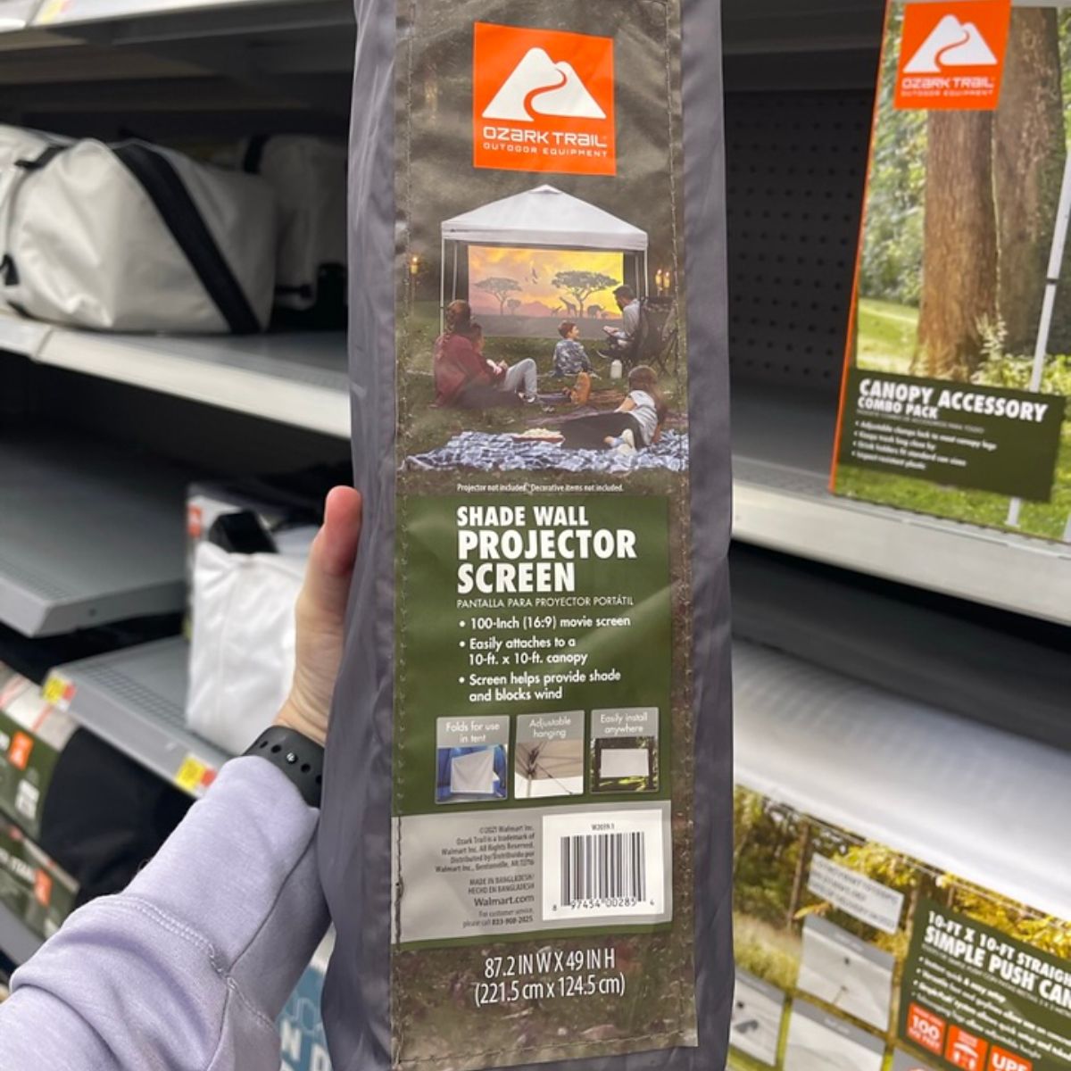 a woman's hand holding an Ozark trail shade wall/ projector screen 16x9 stored in its carrying bag