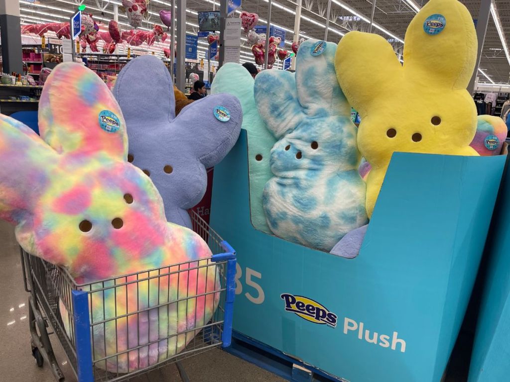 Giant Peeps plush bunnies in a shopping cart and next to the display box