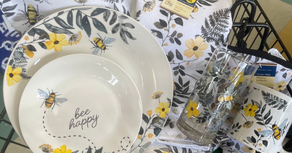 An assortment of dinnerware items: plates, glasses, towles, etc. with bees and yellow flowers on them 