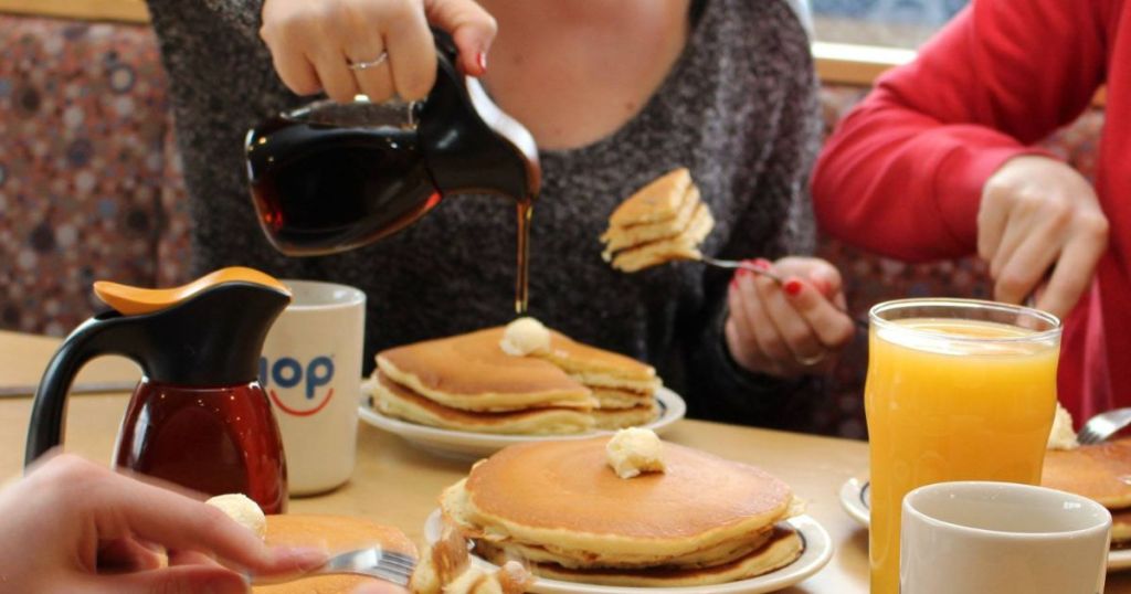 Family sitting at a table eating short stacks of pancakes