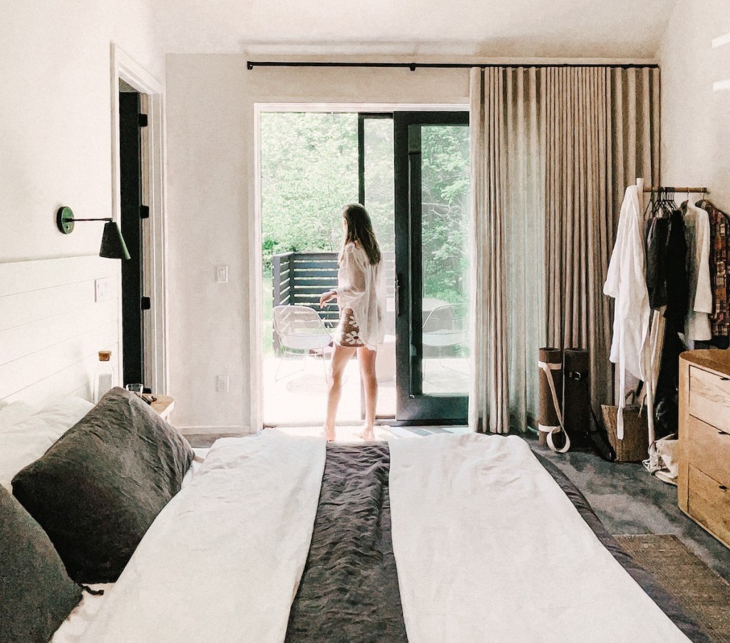 woman standing at patio door with long window shades airbnb essentials