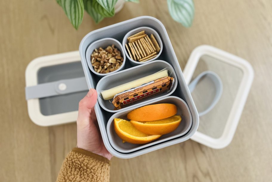 hand holding bentgo style lunch box with food inside