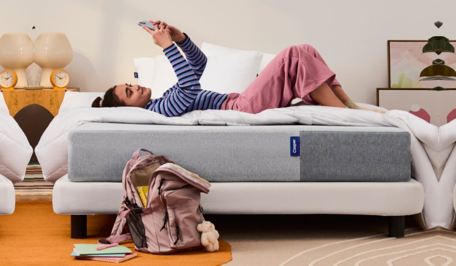 girl laying on bed looking up at phone