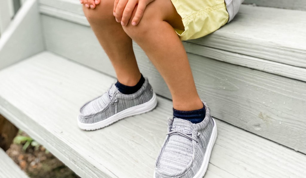 kid sitting on steps in grey shoes