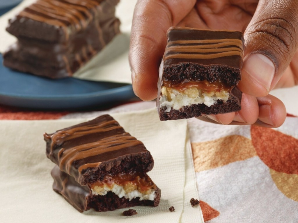 holding a layered chocolate Hostess treat broken in half