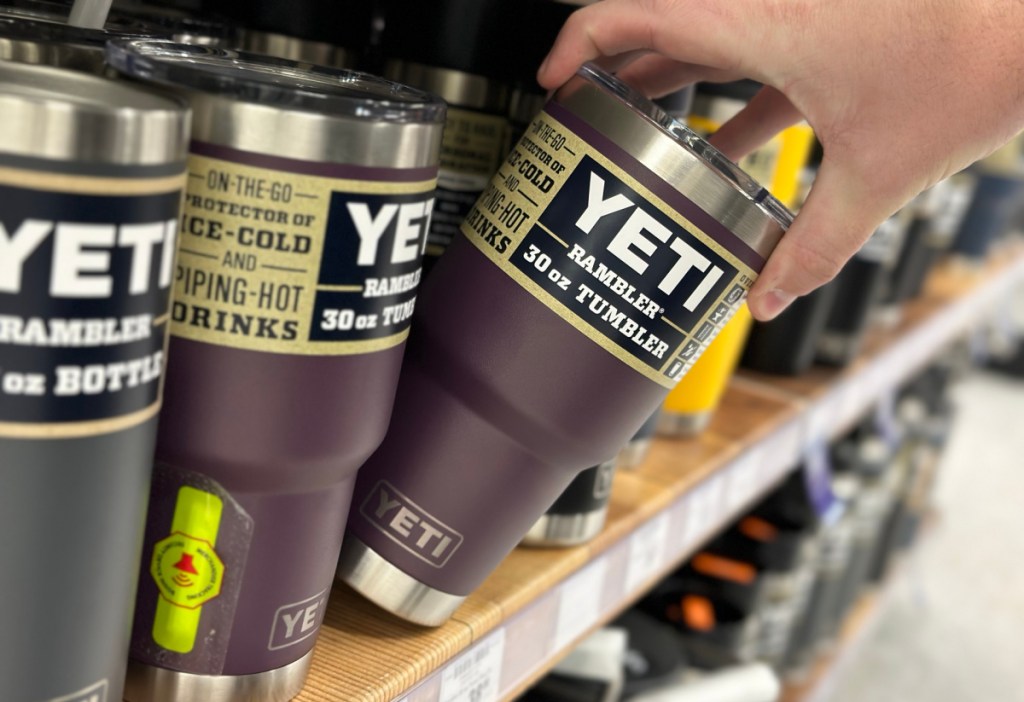 hand tipping a yeti rambler tumbler off a store shelf