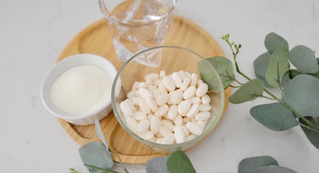 vitamins in bowl next to water and eucalyptus