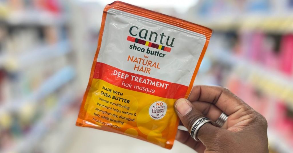 Hand holding a Cantu Deep Treatment Hair Mask packet