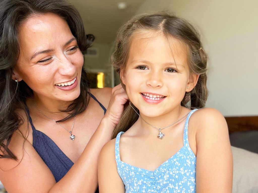 woman putting a necklace on her daughter