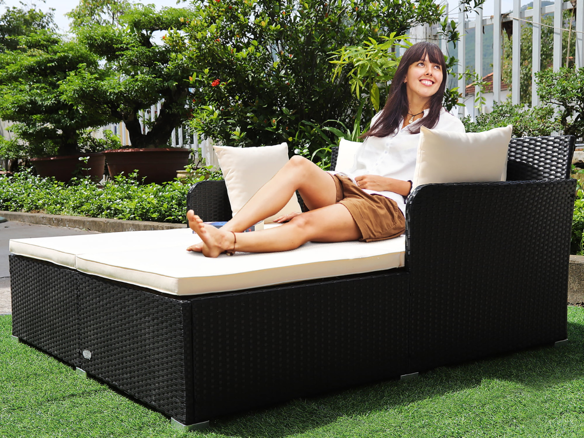 woman lounging on a Costway Outdoor Patio Rattan Daybed