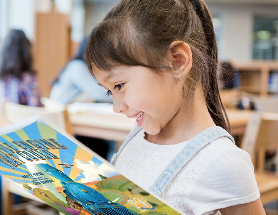 Girl reading a Dolly Parton book club book from the imagination library