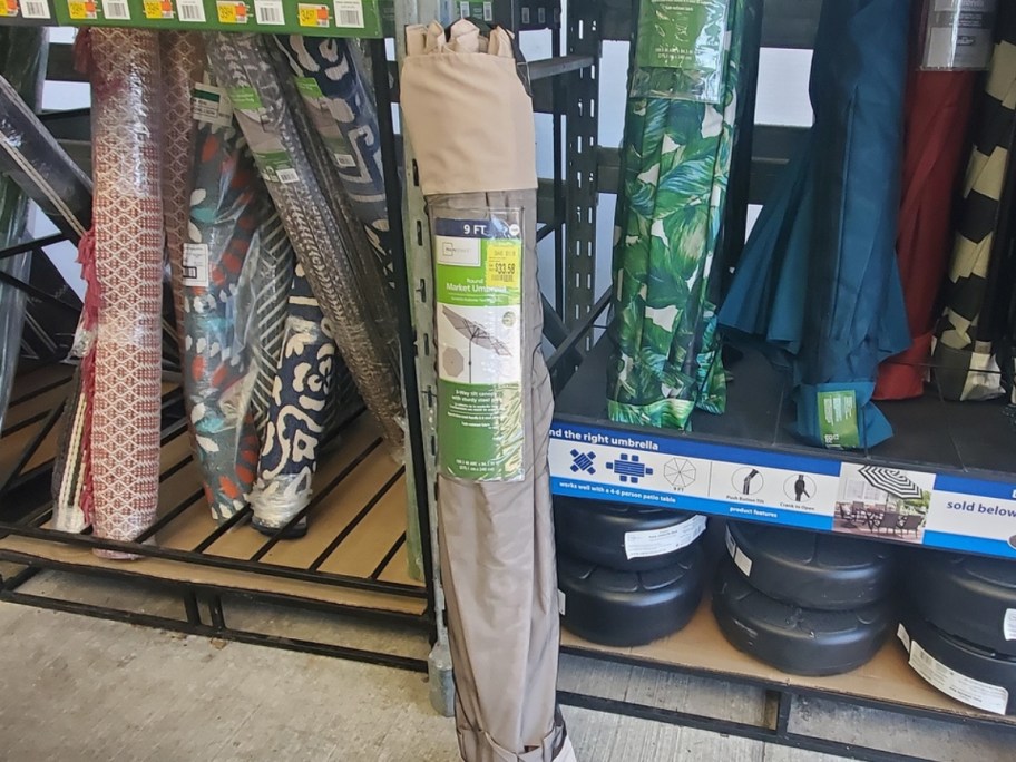 tan patio umbrella in packaging in store with more umbrellas behind it