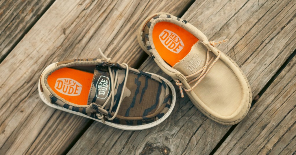 tan and camo print hey dude kids shoes on wood deck