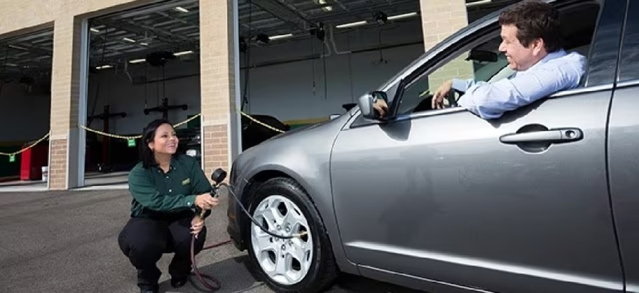 A Just Tires employee providing a complimentary tire pressure check and refilling the tires with air for free