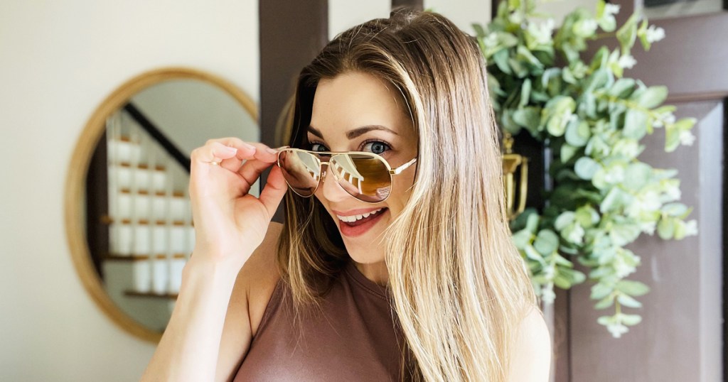 woman holding pair of kate spade sunglasses on her face