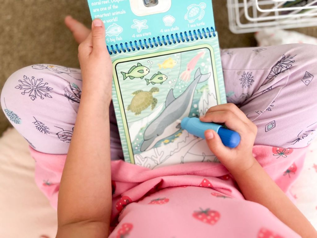 Girl coloring on a Melissa & Doug water wow book