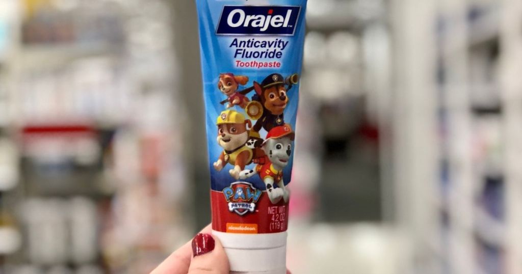 Hand holding up a tube of Kids Orajel Paw Patrol Toothpaste