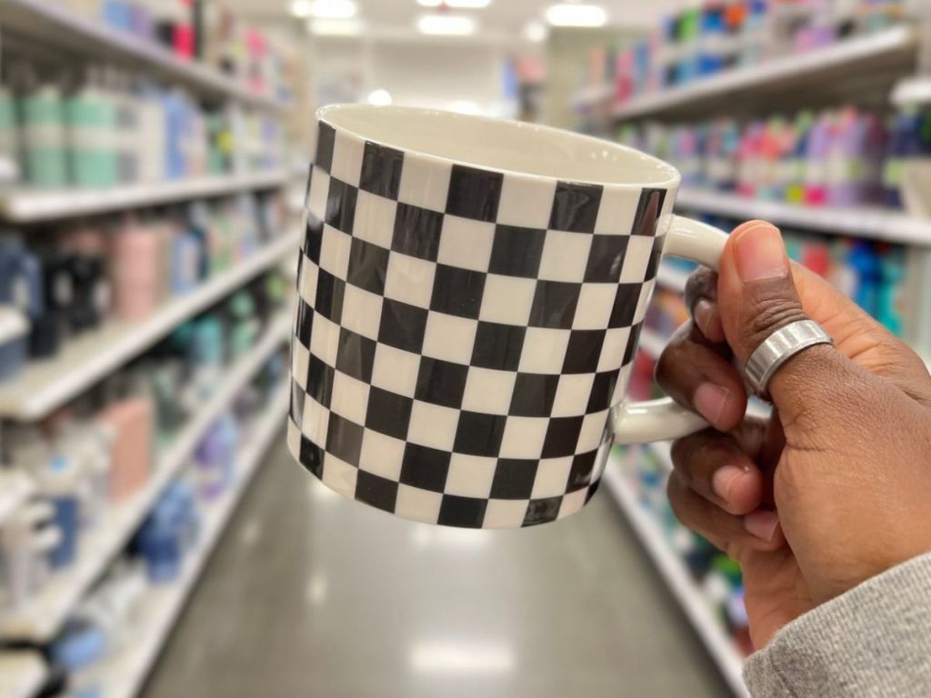 a black and white checkered mug being held by a hand in a grocery store