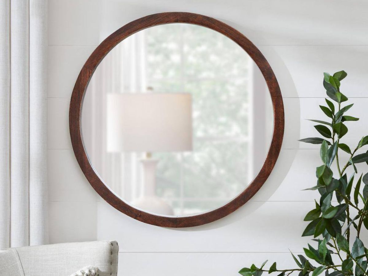 round mirror hanging on wall next to a plant