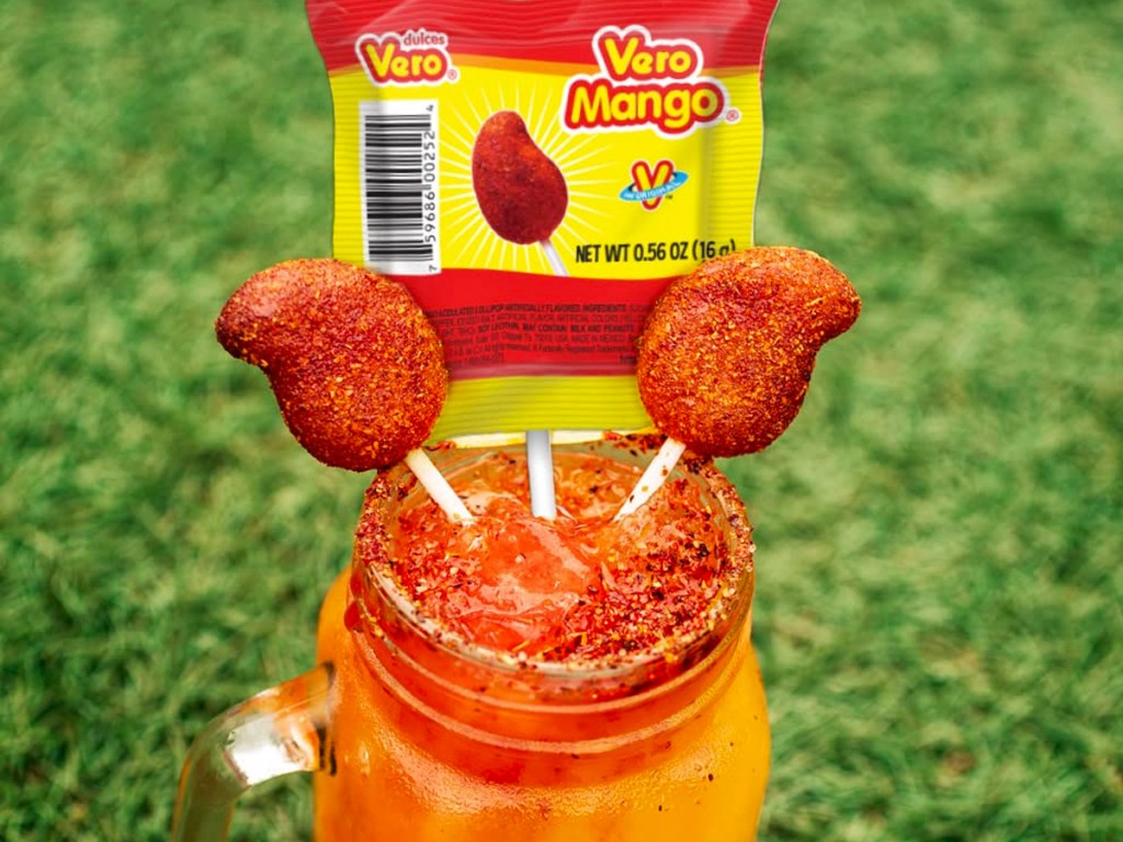 vero mango lollipops stuck in top of red drink in mason jar glass