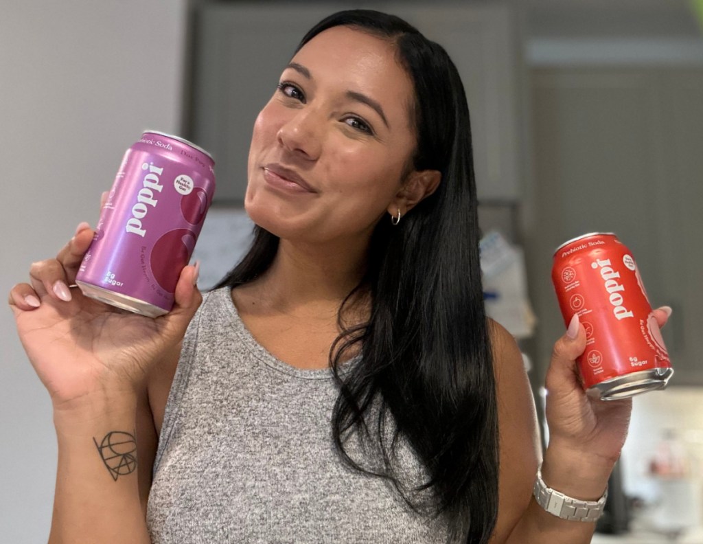Woman holding up cans of Poppi prebiotic soda