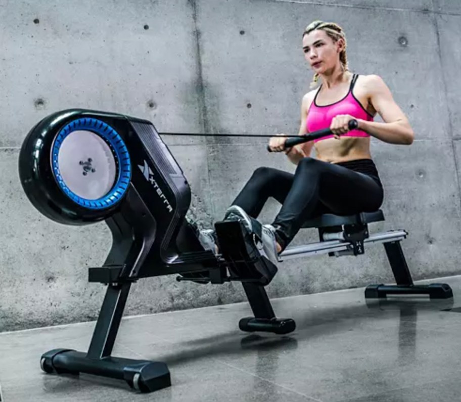 women sitting on black and blue rower in industrial gym