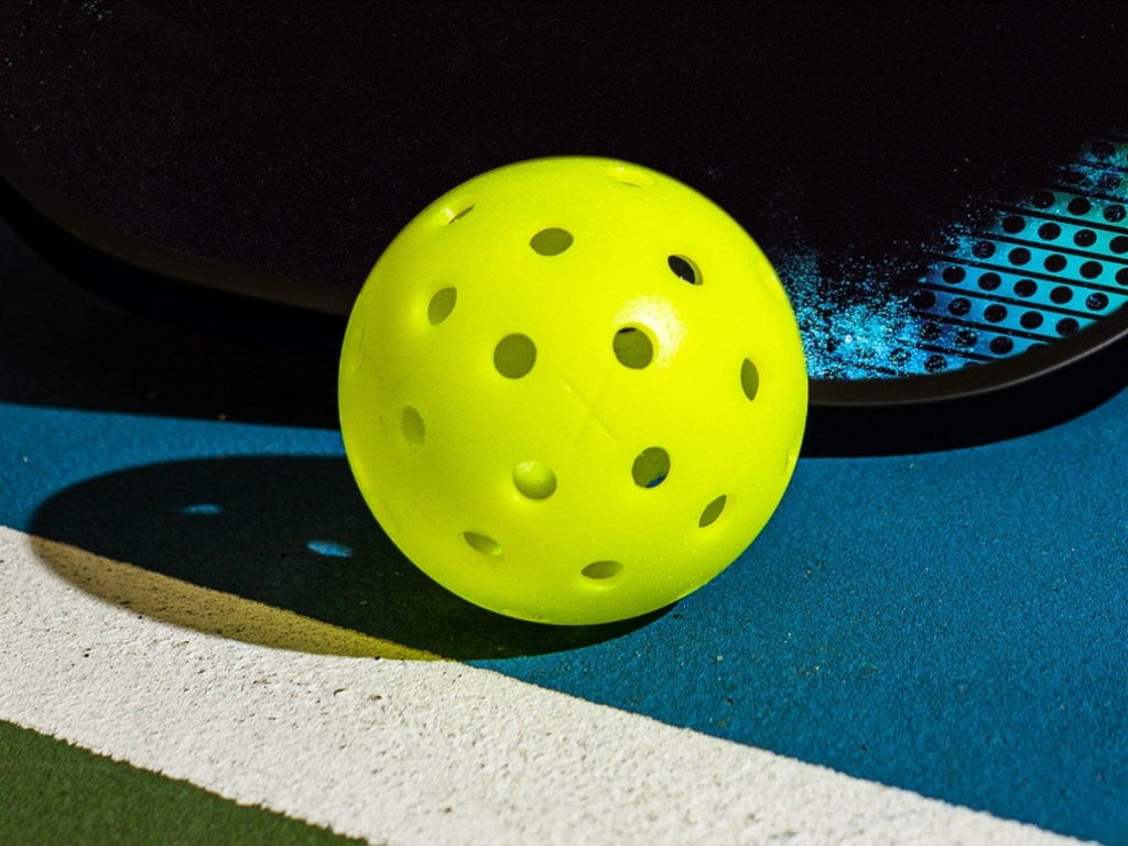 yellow pickleball on blue court