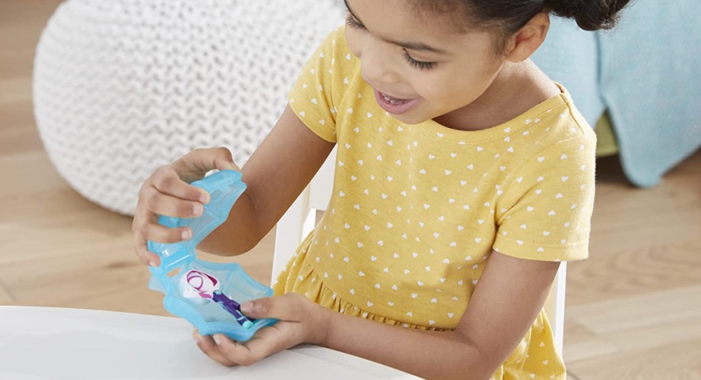 girl opening spider web filled with toy figure inside