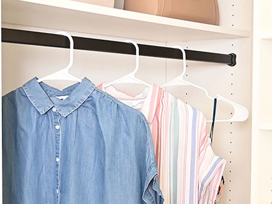 three mainstays white hangers in closet holding tops