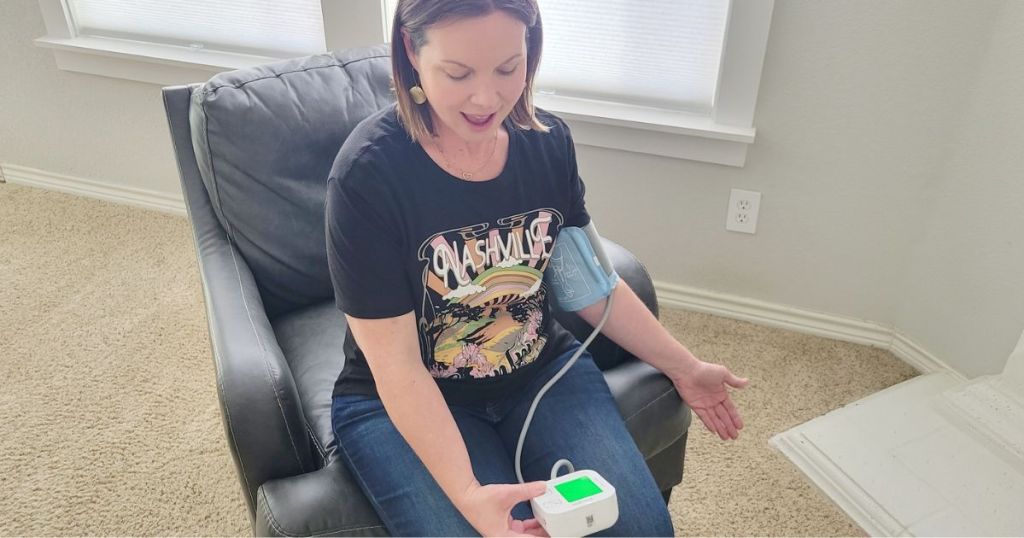 woman sitting in a chair and checking her blood pressure with the iHealth Track Blood Pressure Monitor