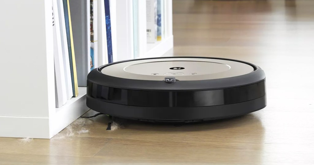 roomba picking up dust near bookcase
