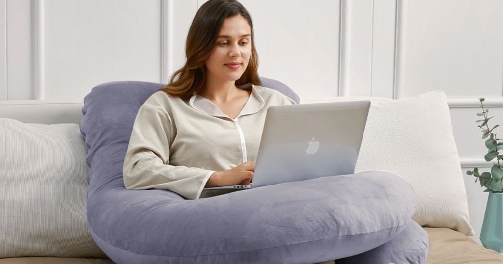 person using laptop while sitting on full body pillow