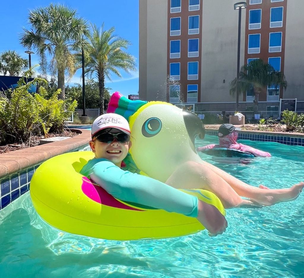 kid sitting in yellow floaty in pool outside