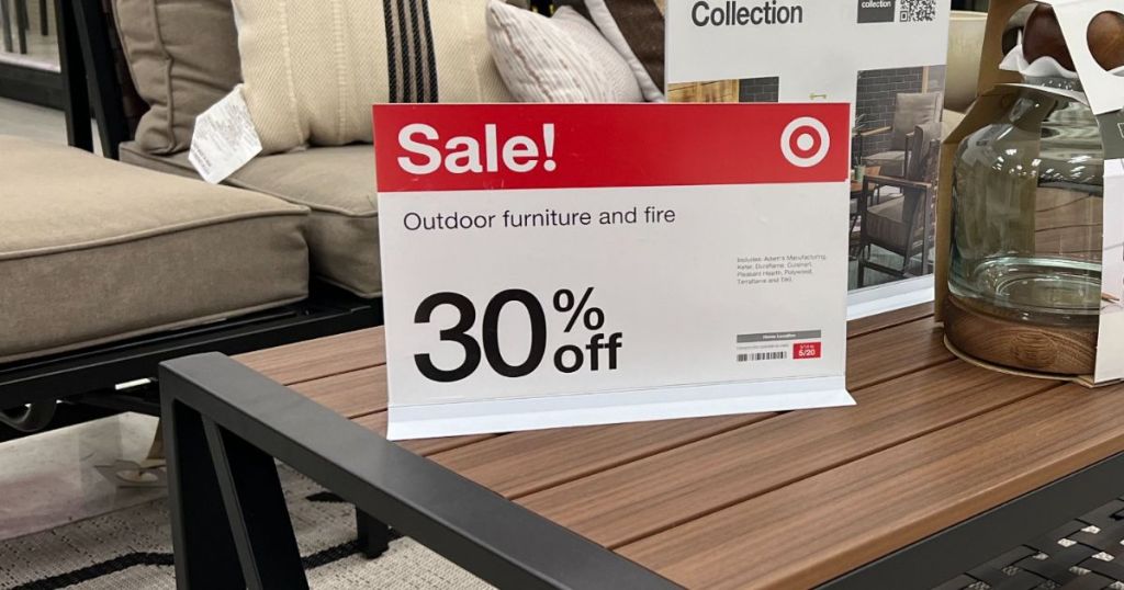 a sign indicating 30% off outdoor furniture target sitting on an outdoor coffee table in the target store