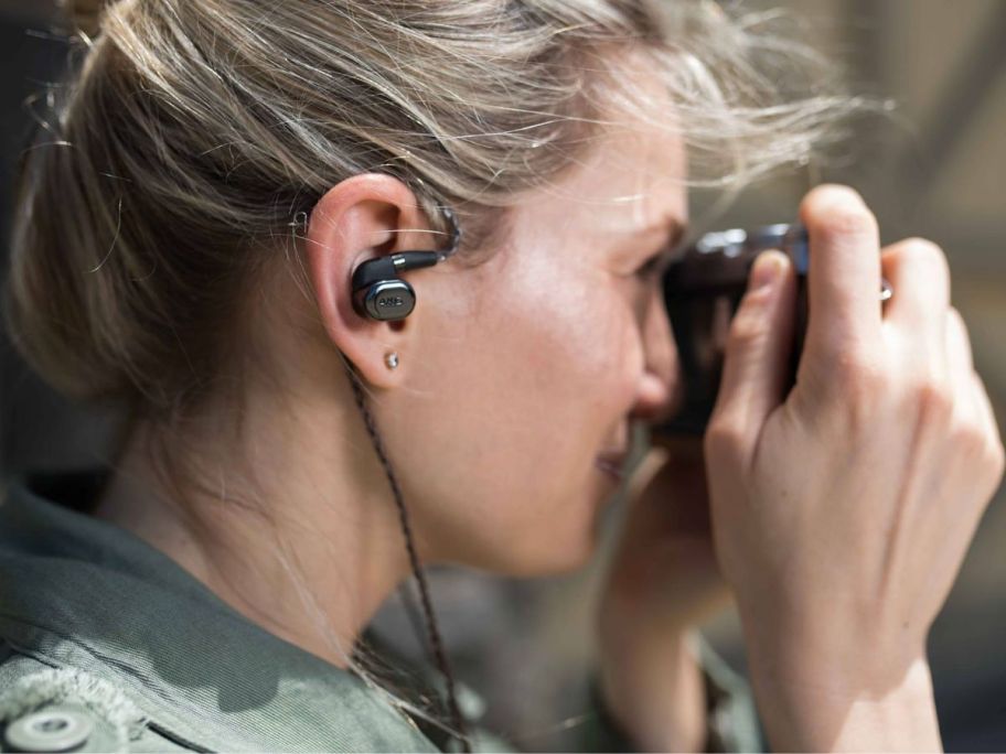 Woman wearing AKG headphones while taking a picture with a camera