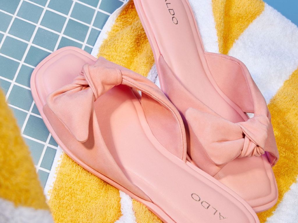 Pair of pink sandals on a yellow and white striped beach towel