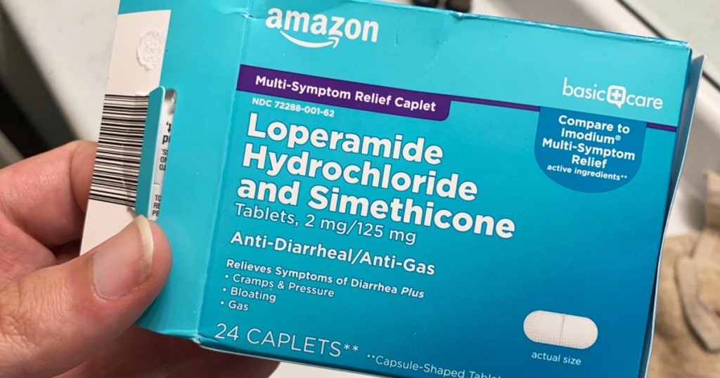 hand holding a blue box of Amazon Basic Care Loperamide Anti-Diarrheal Tablets