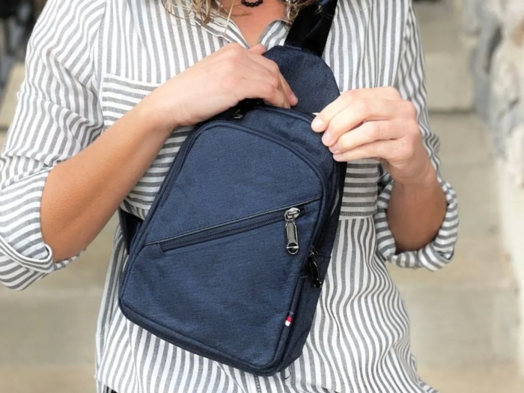 woman with striped shirt wearing a blue sling bag cross the front of her body