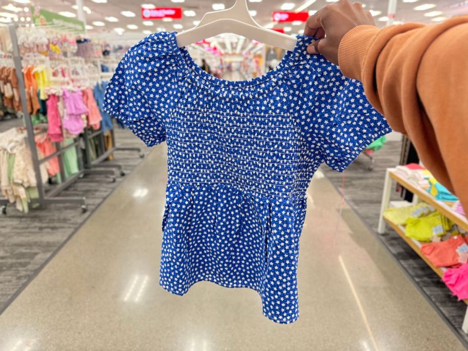 A hand holding aCat and Jack Blue and White Shirt with Stars on it 