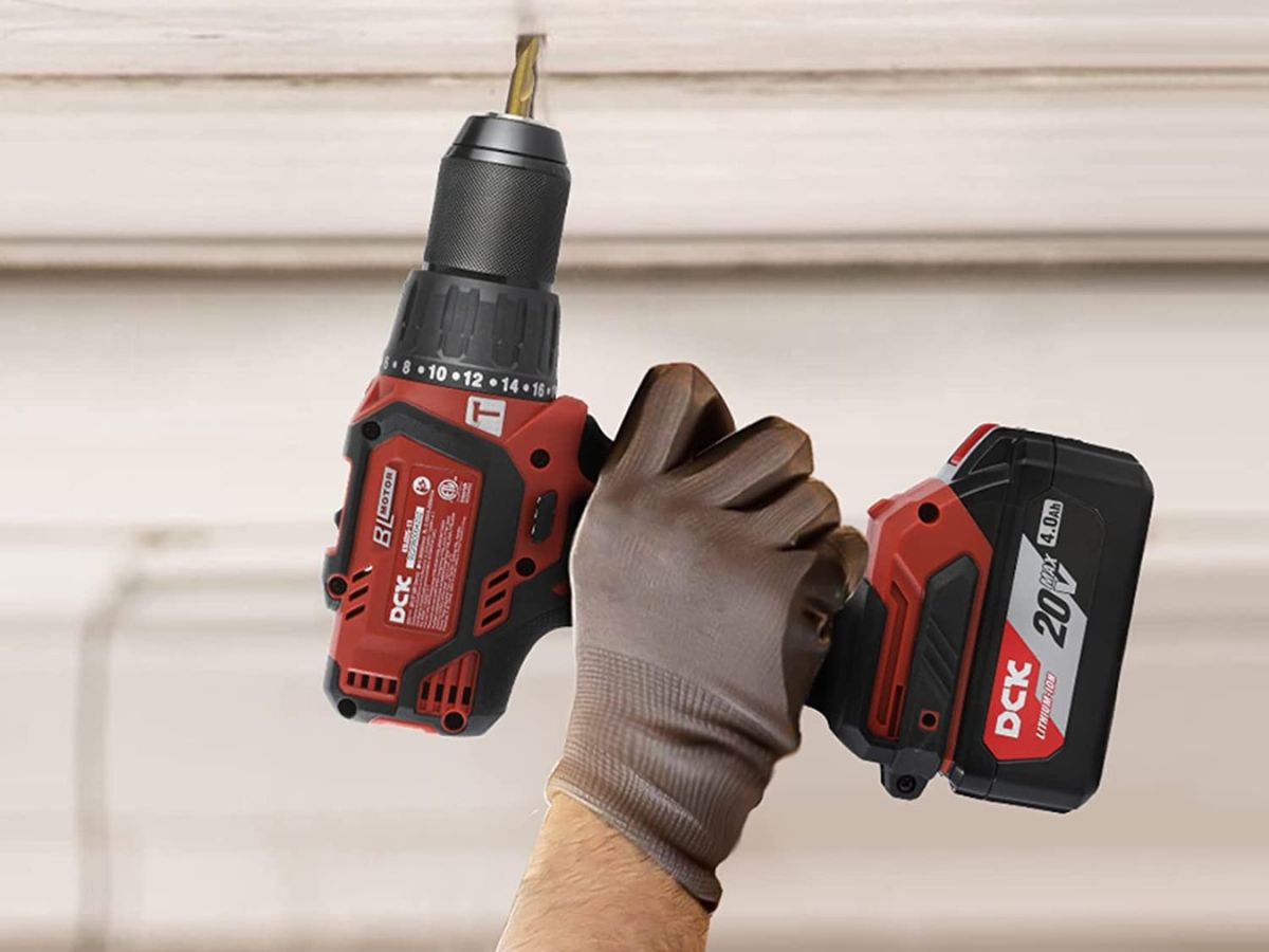 person using DCK 20V drill in wall