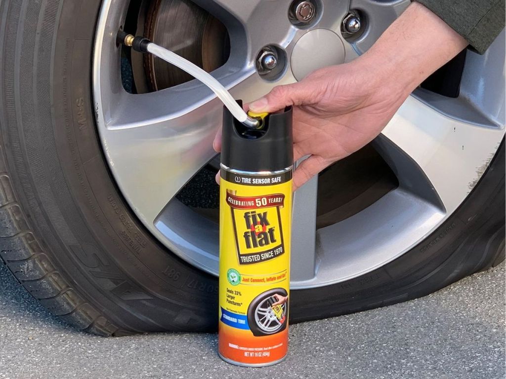 Person attaching a Fix a Flat can to a tire