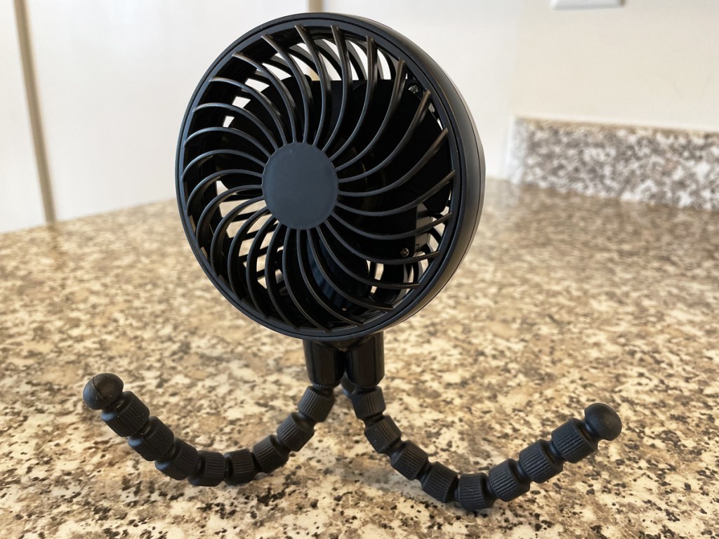 black fan with tripod legs on kitchen counter
