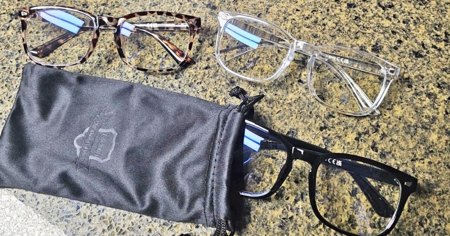 three pairs of glasses on counter with one coming out of a black bag