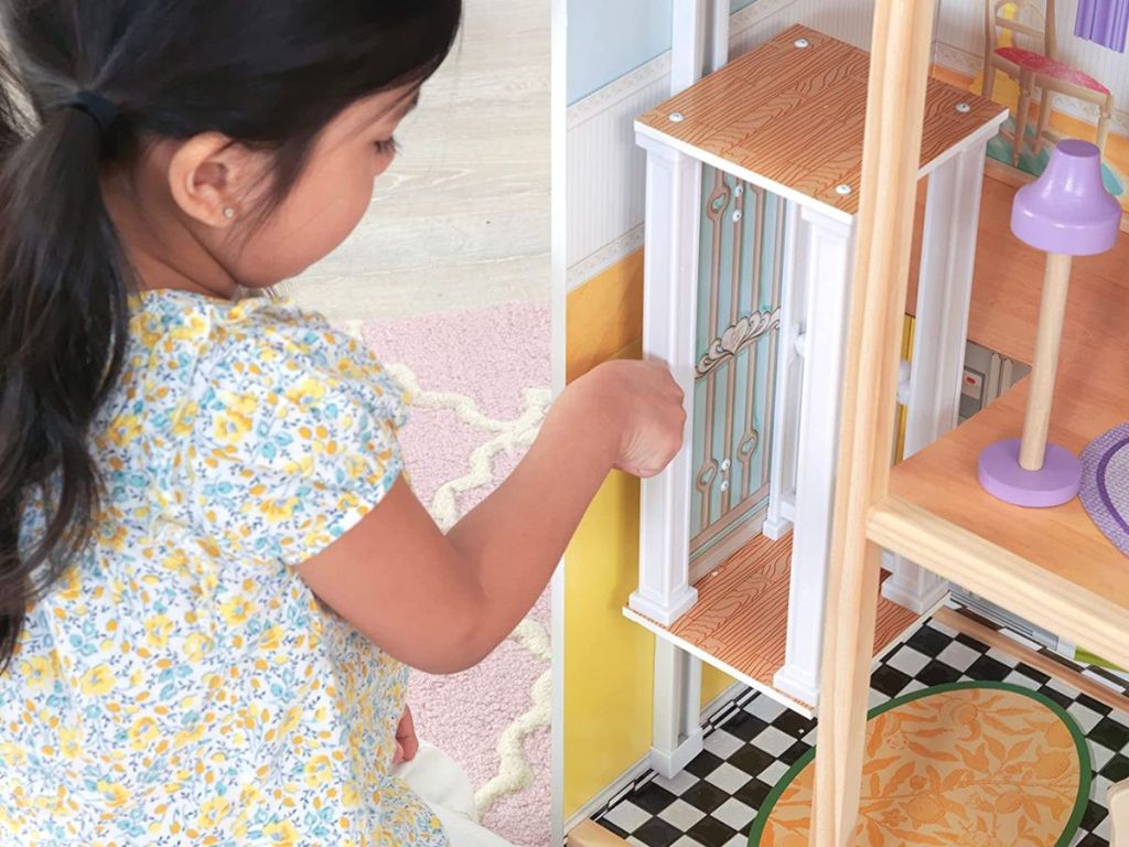 Little girl playing with the elevator in a dollhouse